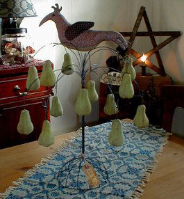Colorful 11” bird presiding over an array of stuffed and painted cloth pears.