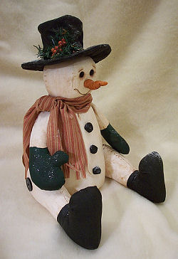 This 13” seated, primitive snowman is made of painted muslin with a clay nose. 